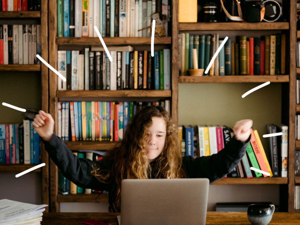 Student with celebratory arms in air studying at laptop computer - high quality online tutoring with Bray Tutoring